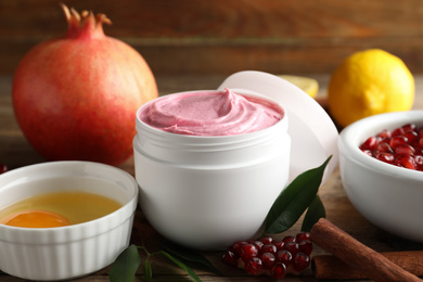 Photo of Natural homemade mask, pomegranate and ingredients on wooden table, closeup