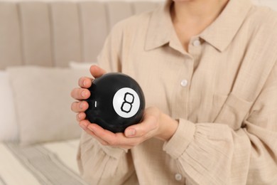 Woman holding magic eight ball indoors, closeup