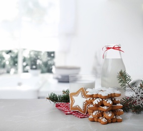 Image of Christmas cookies and milk on marble table with fir tree branches in kitchen 