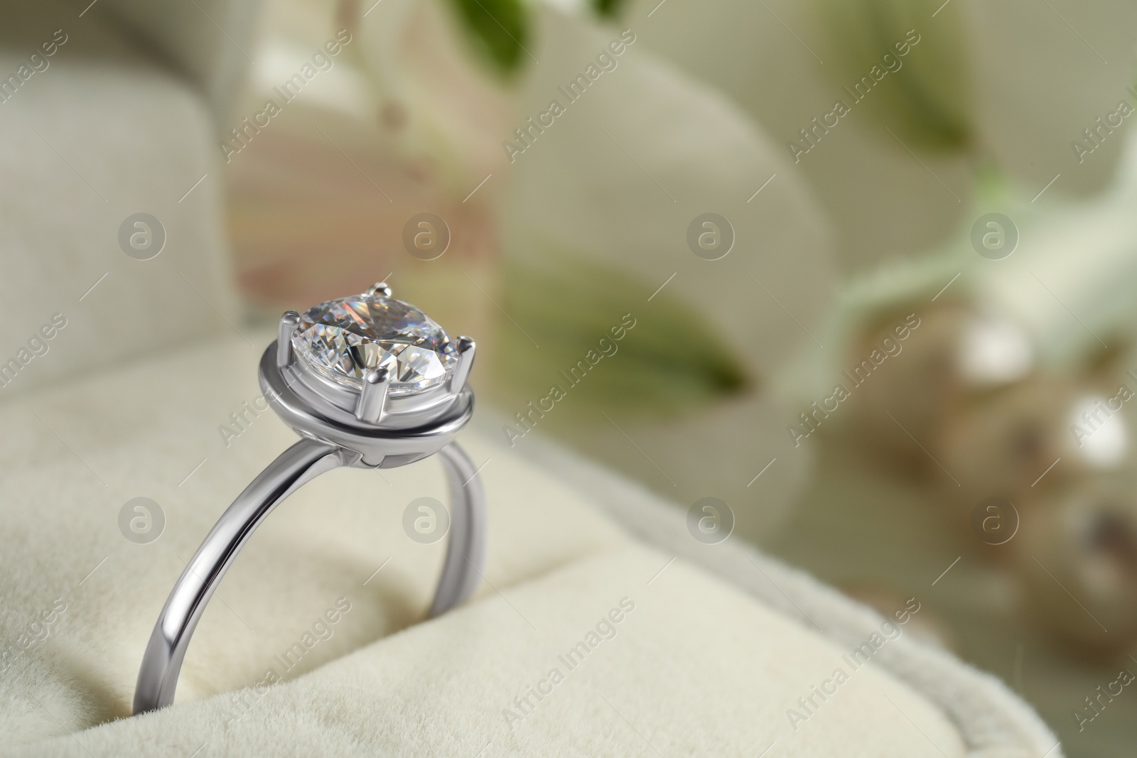 Photo of Beautiful engagement ring in box against blurred background, closeup. Space for text