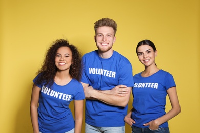 Team of volunteers in uniform on yellow background
