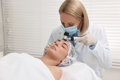 Photo of Dermatologist with dermatoscope examining patient`s face in clinic