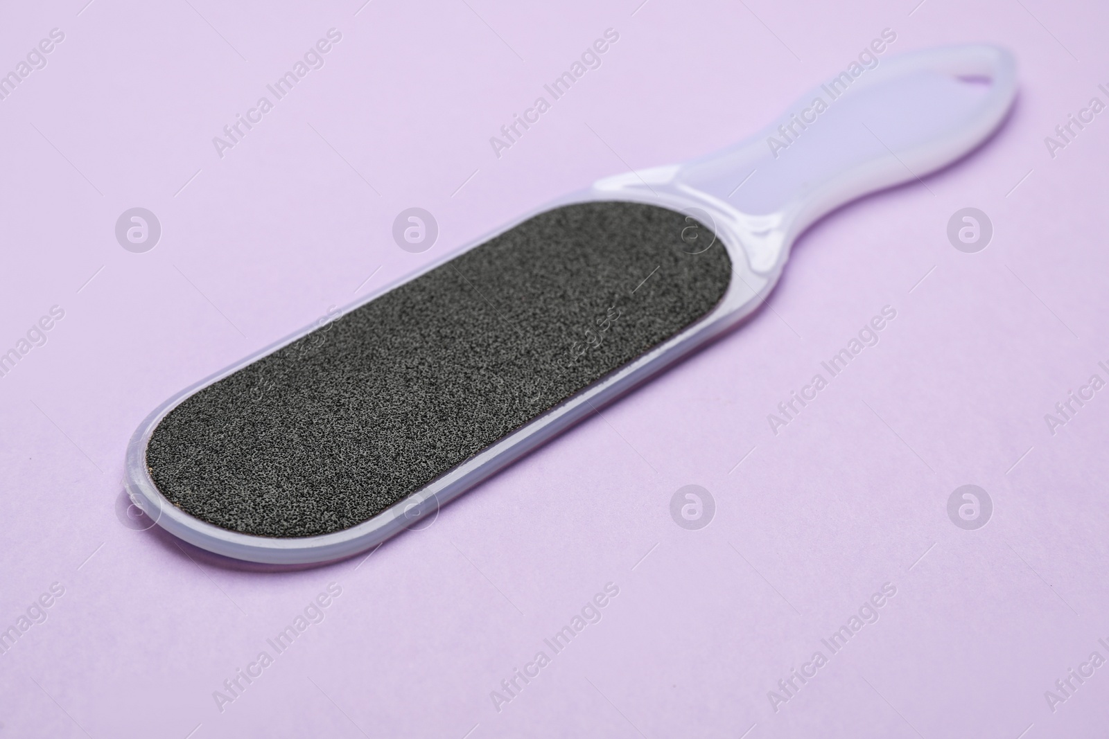 Photo of Foot file on violet background, closeup. Pedicure tool