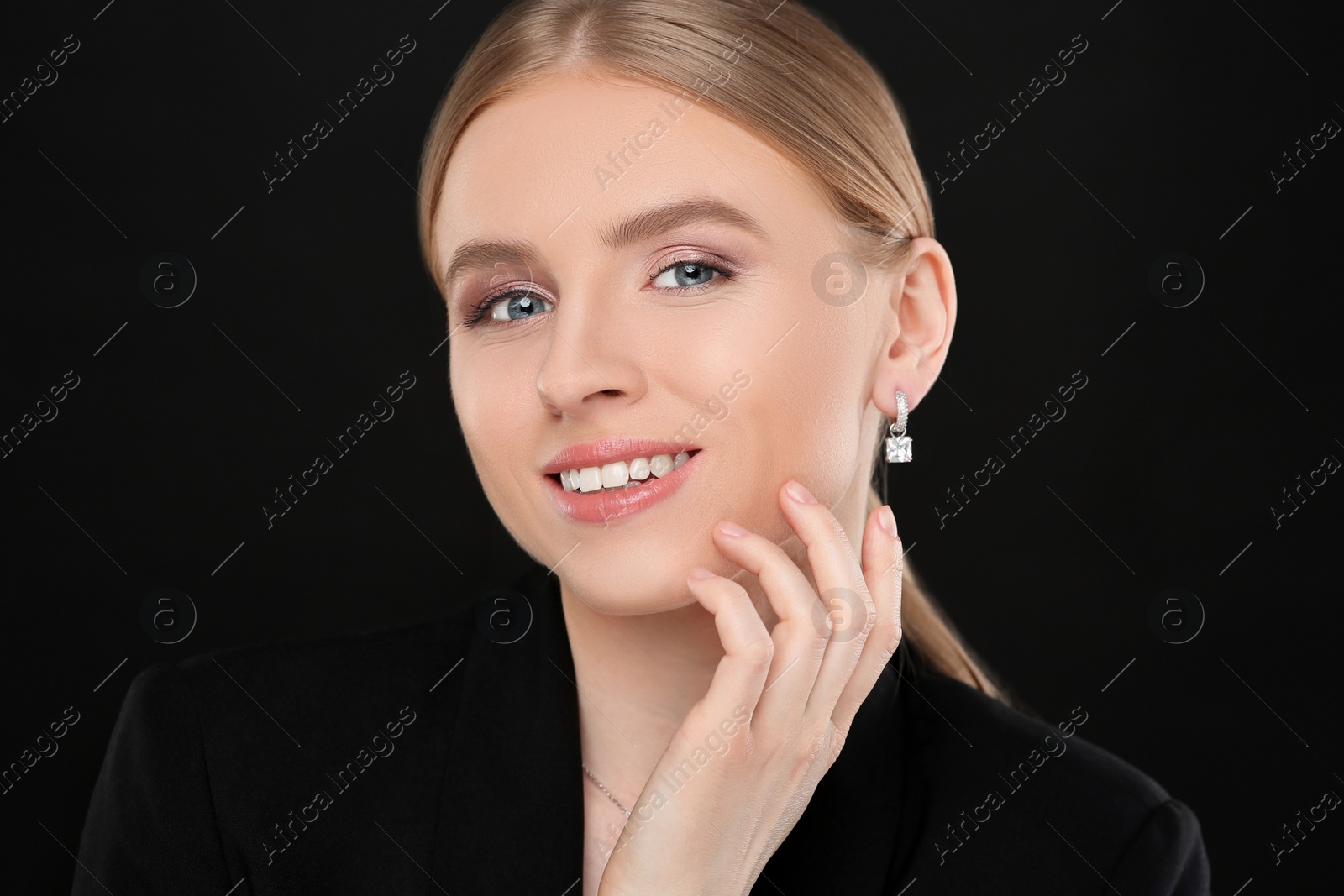 Photo of Beautiful young woman with elegant earrings on black background