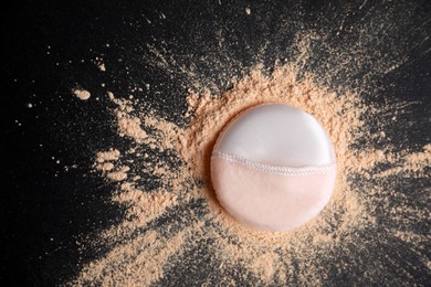 Photo of Puff applicator and loose face powder on black background, flat lay