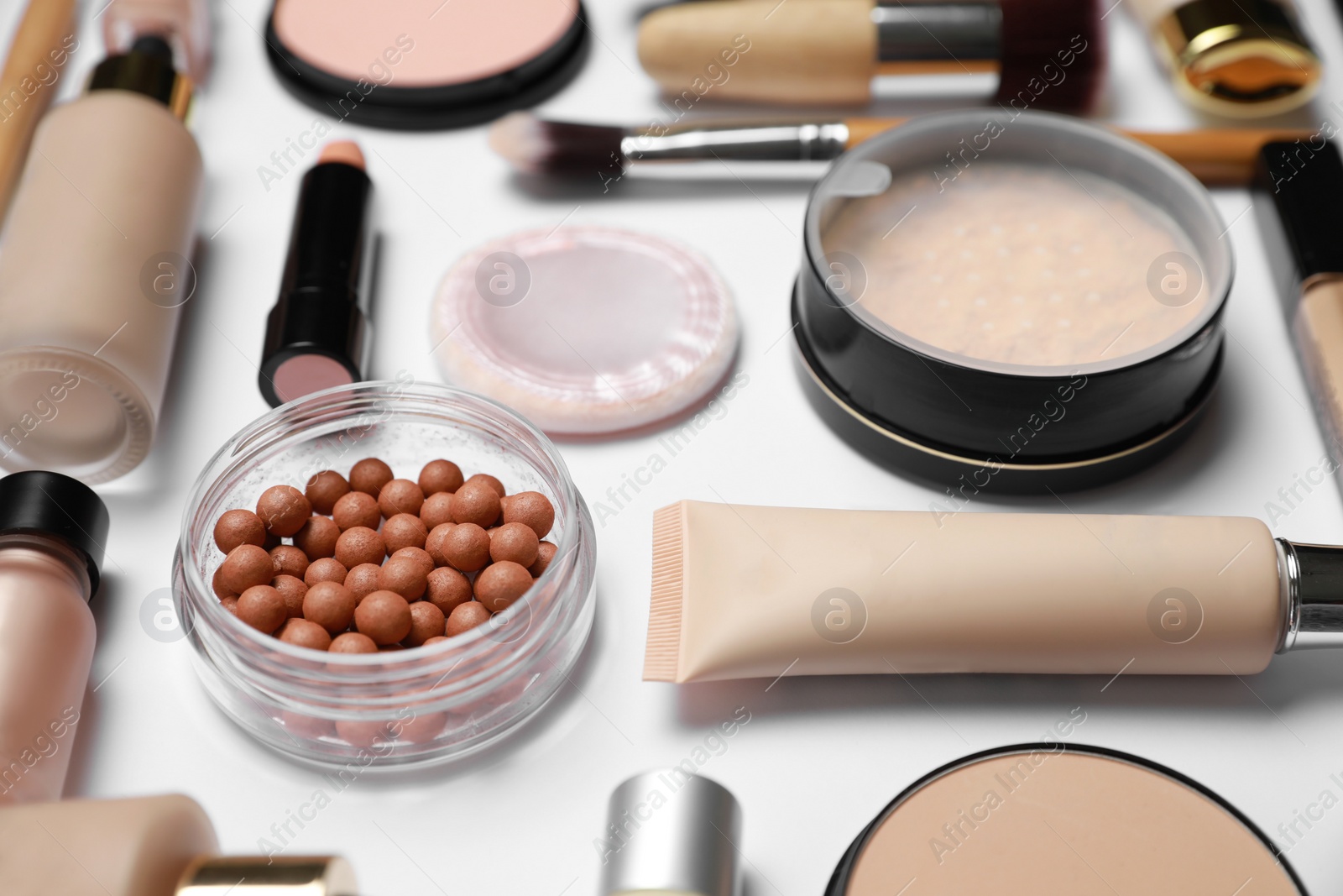 Photo of Face powders and other makeup products on white background, closeup