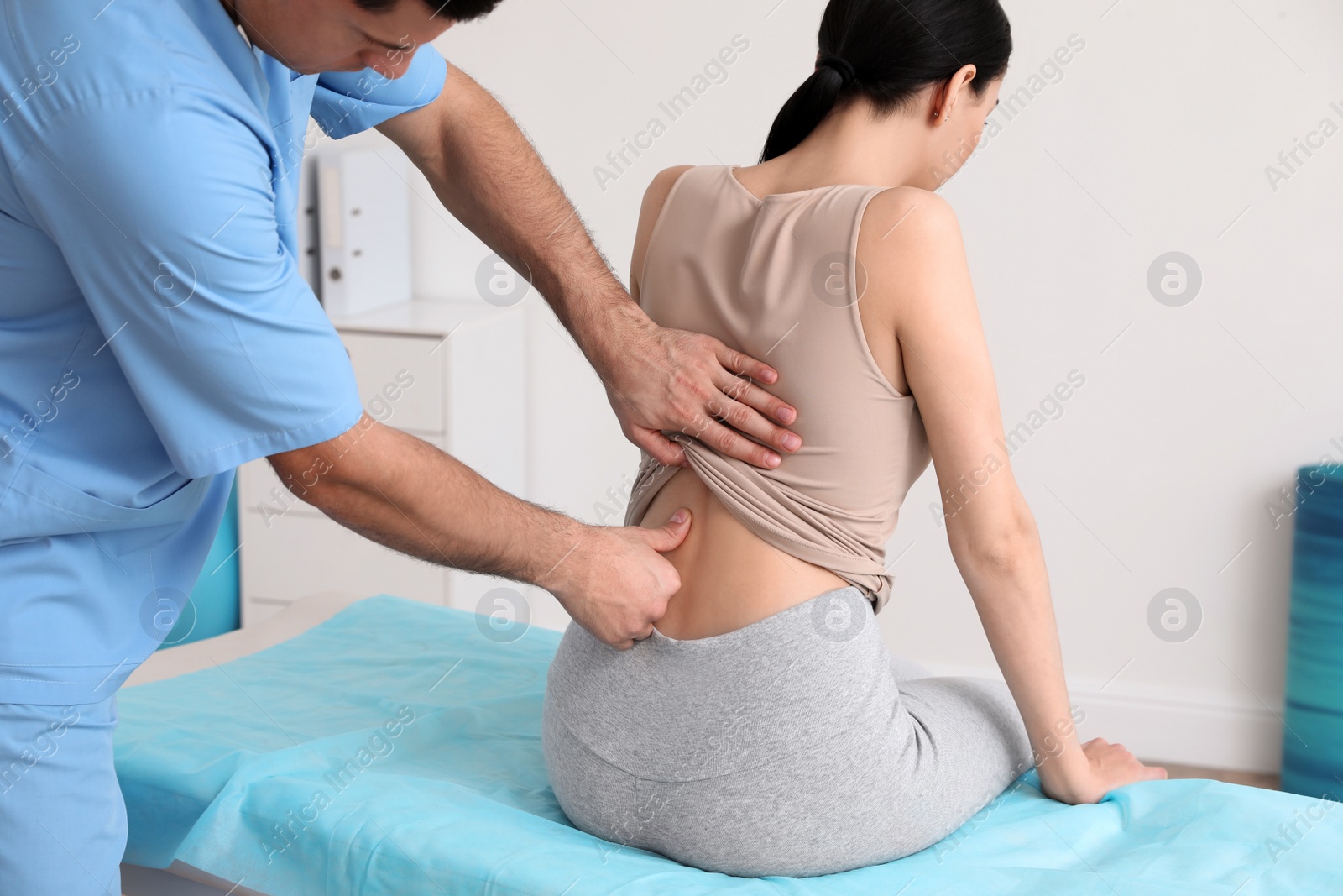 Photo of Orthopedist examining woman's back in clinic. Scoliosis treatment