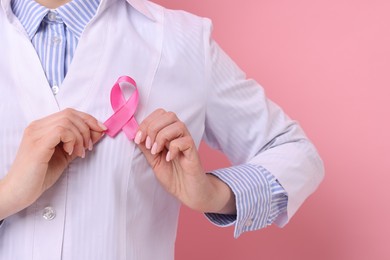 Photo of Mammologist with pink ribbon against color background, closeup. Breast cancer awareness.