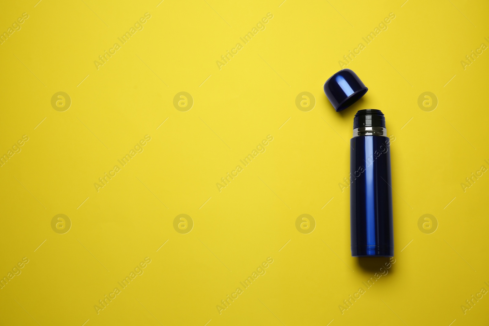 Photo of Blue thermos on yellow background, top view. Space for text