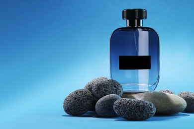 Photo of Stylish presentation of luxury men`s perfume on stones against light blue background. Space for text