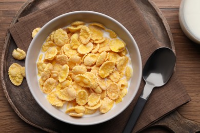 Photo of Tasty cornflakes with milk in bowl served on wooden table, flat lay