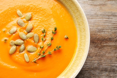 Photo of Bowl with tasty pumpkin soup on table, closeup