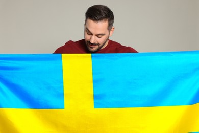 Man with flag of Sweden on light grey background