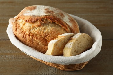 Basket with fresh bread on wooden table