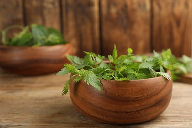 Fresh stinging nettle leaves in bowl on wooden table