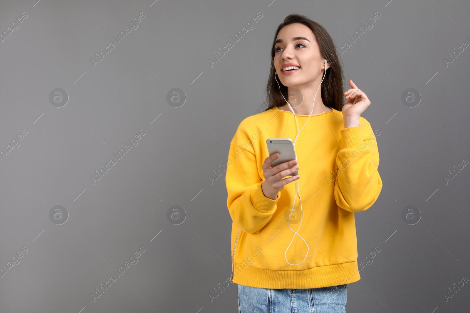 Photo of Young woman using phone for listening to music against color background