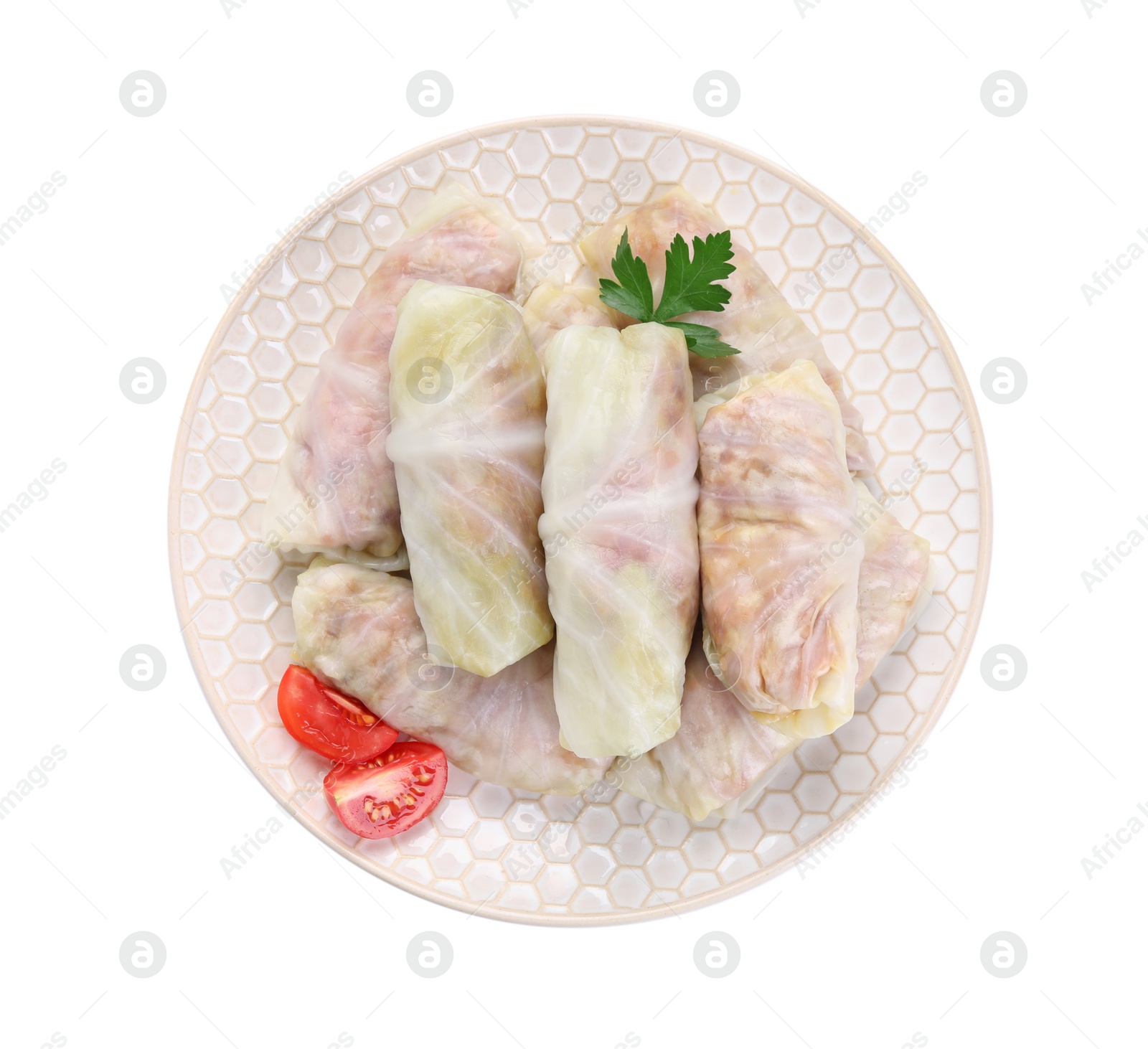 Photo of Plate with uncooked stuffed cabbage rolls, tomato and parsley isolated on white, top view