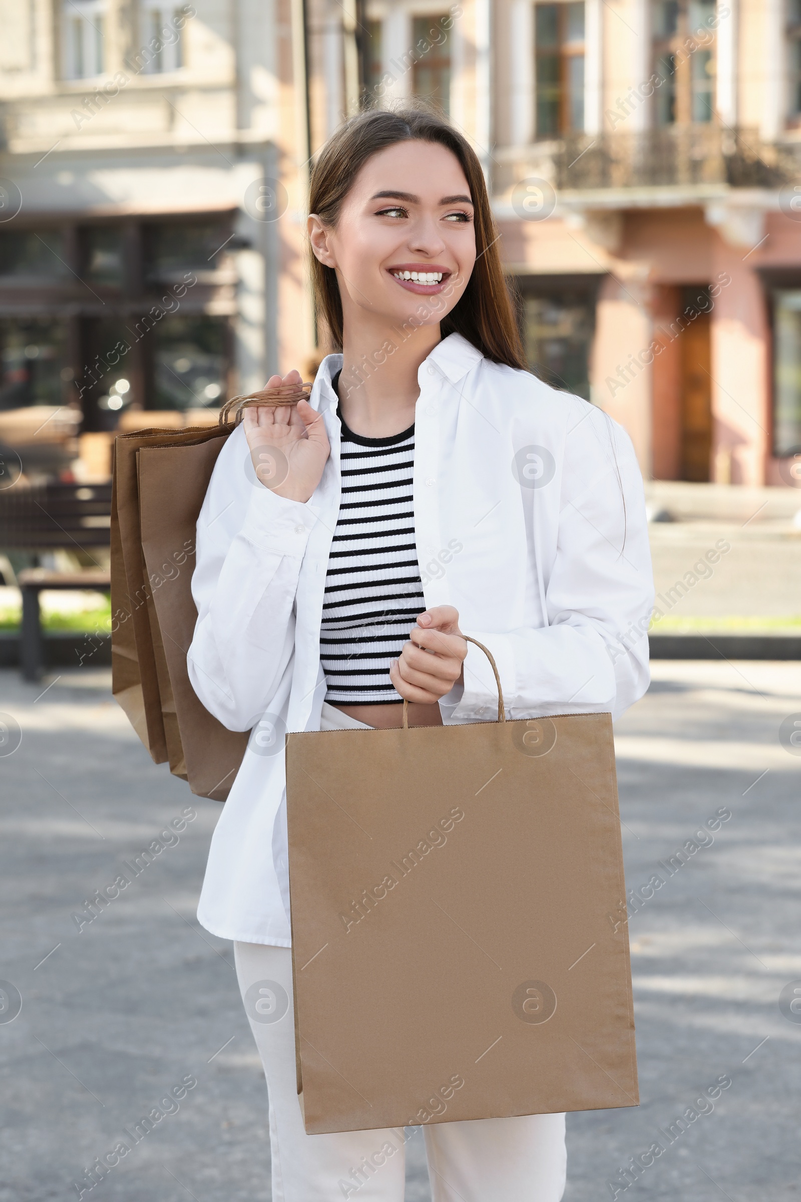 Photo of Beautiful young woman with shopping bags on city street