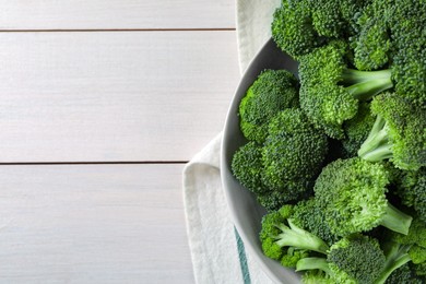 Bowl of fresh raw broccoli on white wooden table, top view. Space for text