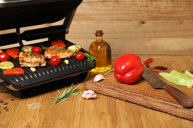 Photo of Electric grill with different products on wooden table