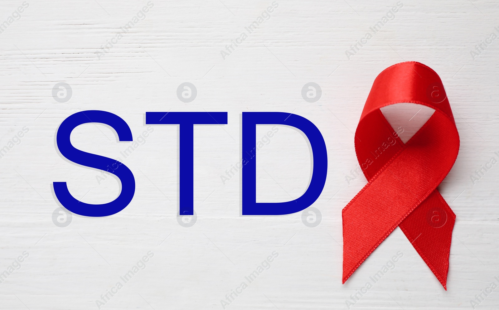 Image of Red awareness ribbon and abbreviation STD on white wooden background, top view 
