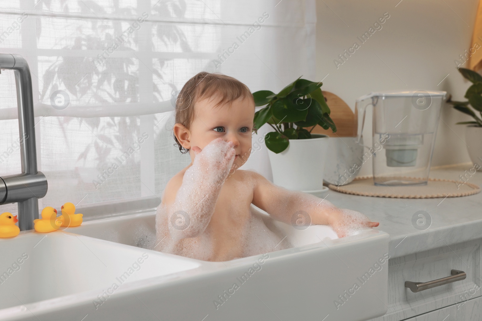 Photo of Cute little baby bathing in sink at home