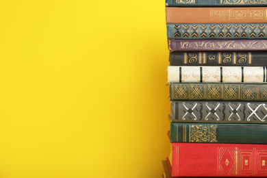 Stack of hardcover books on yellow background. Space for text