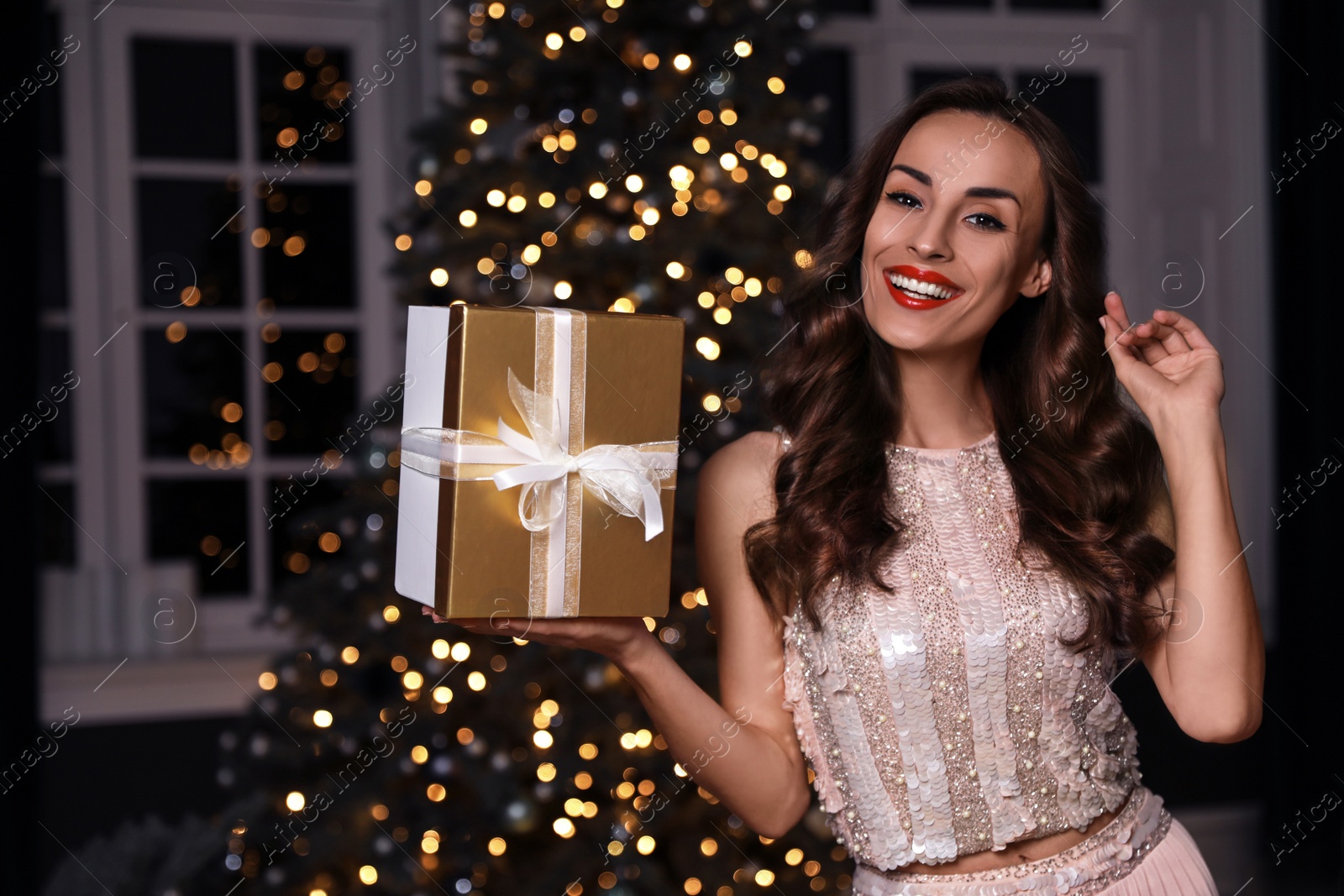 Photo of Beautiful woman with gift box in decorated room. Christmas celebration