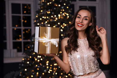 Photo of Beautiful woman with gift box in decorated room. Christmas celebration