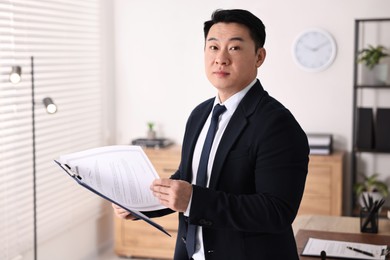 Portrait of confident notary with clipboard in office