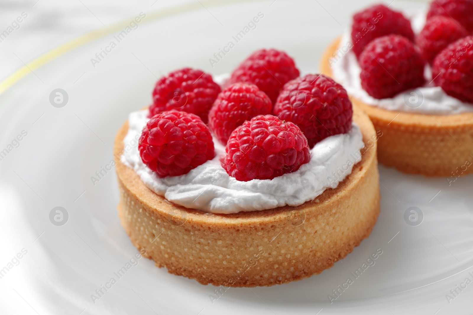 Photo of Plate with raspberry tarts, closeup. Delicious pastries