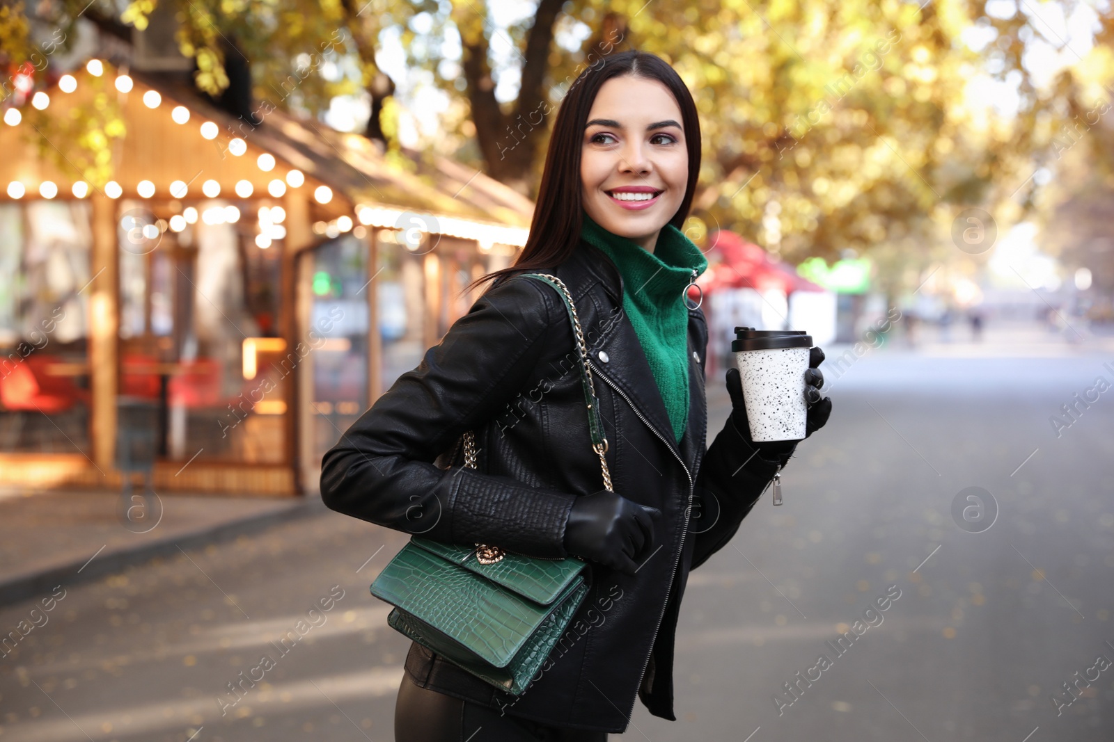 Photo of Beautiful young woman with cup of coffee on city street. Autumn walk