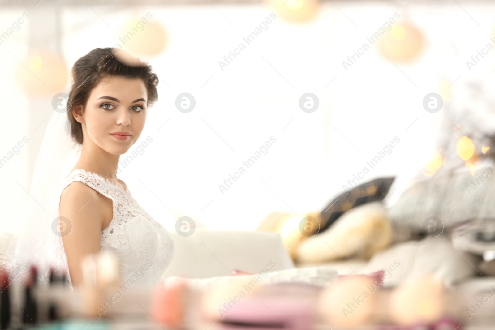 Photo of Reflection of beautiful young bride with makeup created by professional artist in mirror