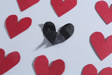 Photo of Halves of torn paper heart and red decorative hearts on gray background, above view. Breakup concept