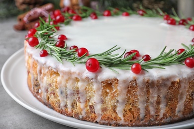 Traditional Christmas cake decorated with rosemary and cranberries on table, closeup