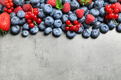 Different fresh berries on grey background, flat lay. Space for text