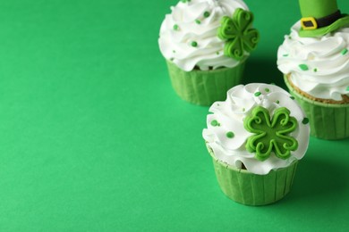 Photo of St. Patrick's day party. Tasty festively decorated cupcakes on green table, closeup. Space for text