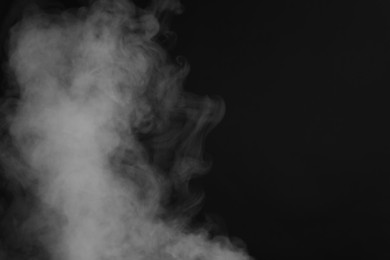 Photo of Beautiful smoke on dark background, space for text
