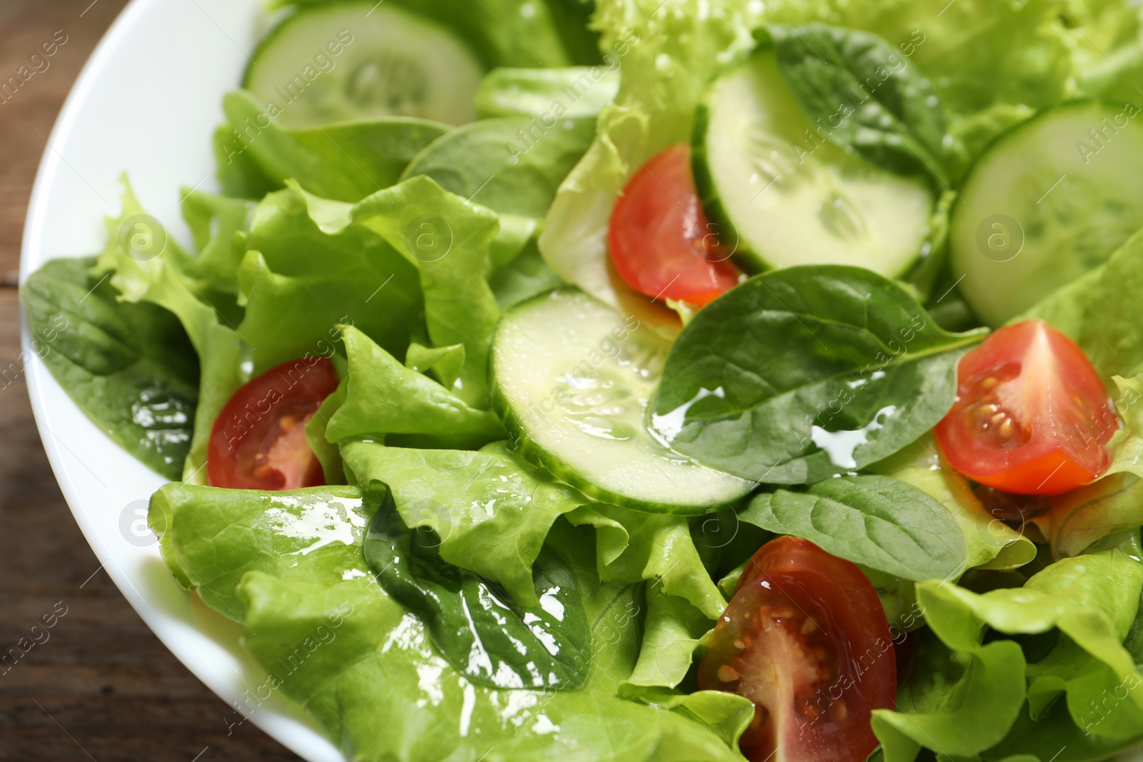 Photo of Delicious salad in bowl on wooden table, closeup