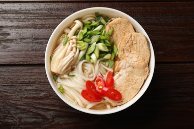 Photo of Delicious ramen with meat and mushrooms in bowl on wooden table, top view. Noodle soup