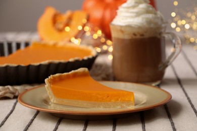 Photo of Fresh homemade pumpkin pie and cup of cocoa with whipped cream on table