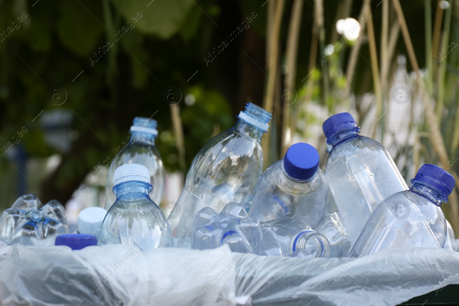 Photo of Many used plastic bottles in trash bin outdoors, closeup. Recycling problem