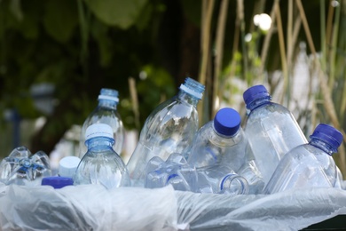 Photo of Many used plastic bottles in trash bin outdoors, closeup. Recycling problem
