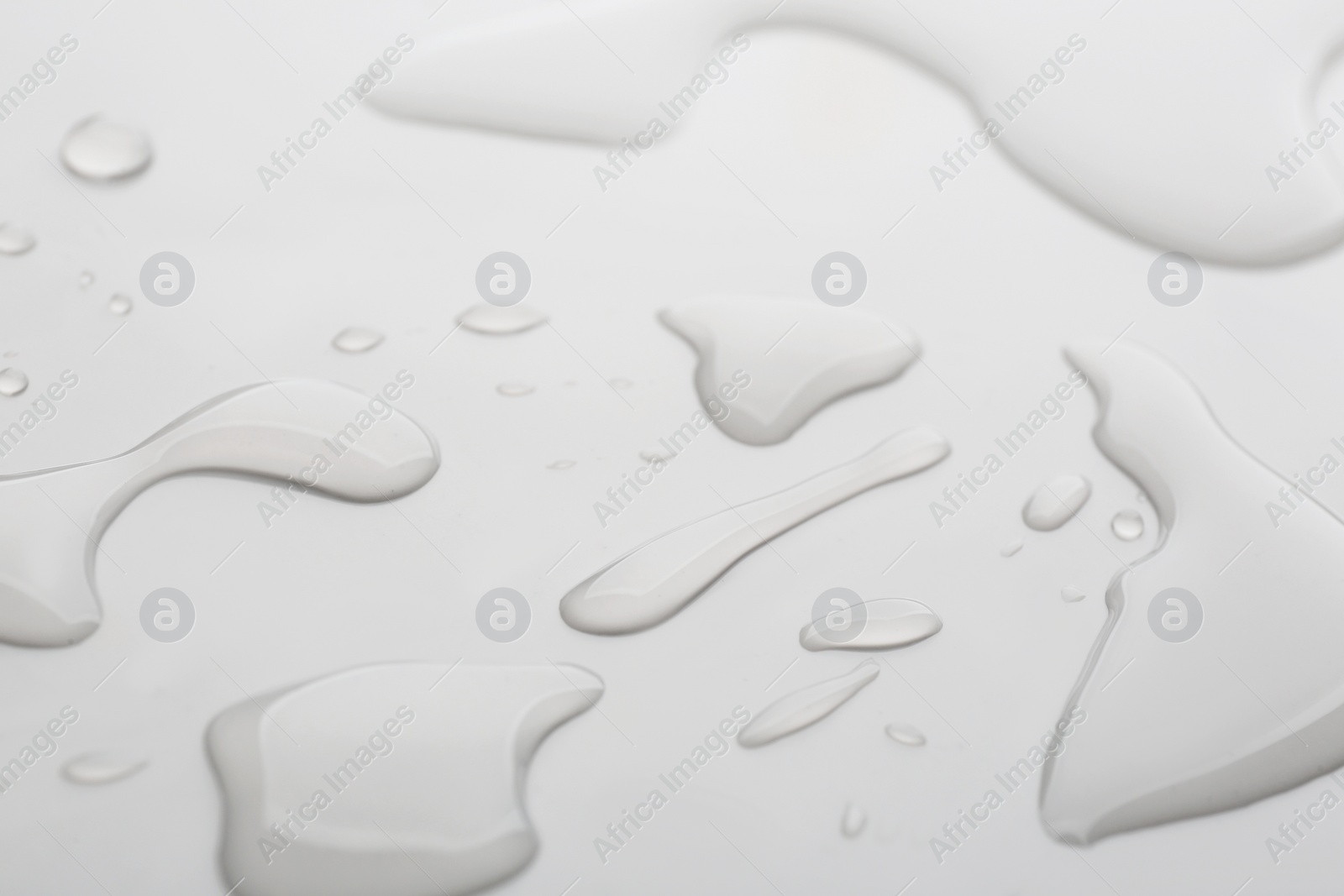 Photo of Drops of spilled water on grey background, closeup