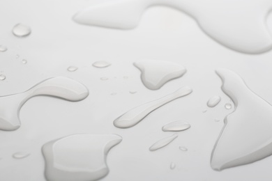 Photo of Drops of spilled water on grey background, closeup