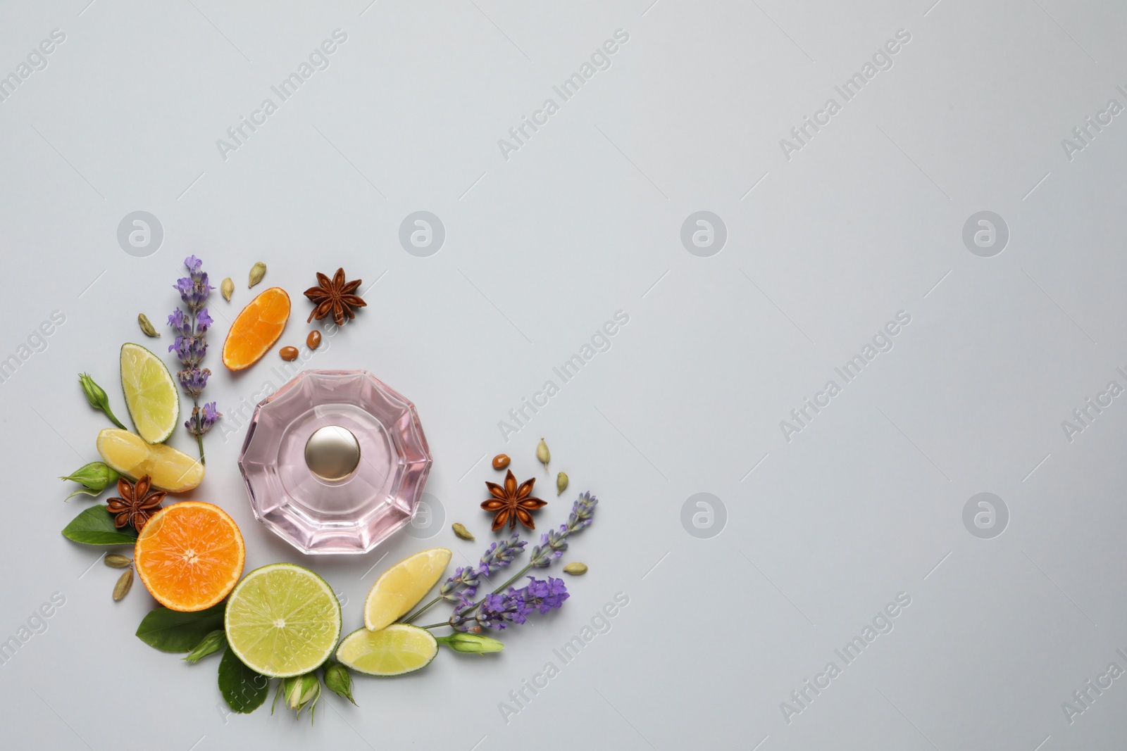 Photo of Flat lay composition with bottle of perfume, citrus fruits and flowers on light grey background. Space for text