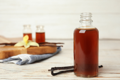 Aromatic homemade vanilla extract on white wooden table. Space for text