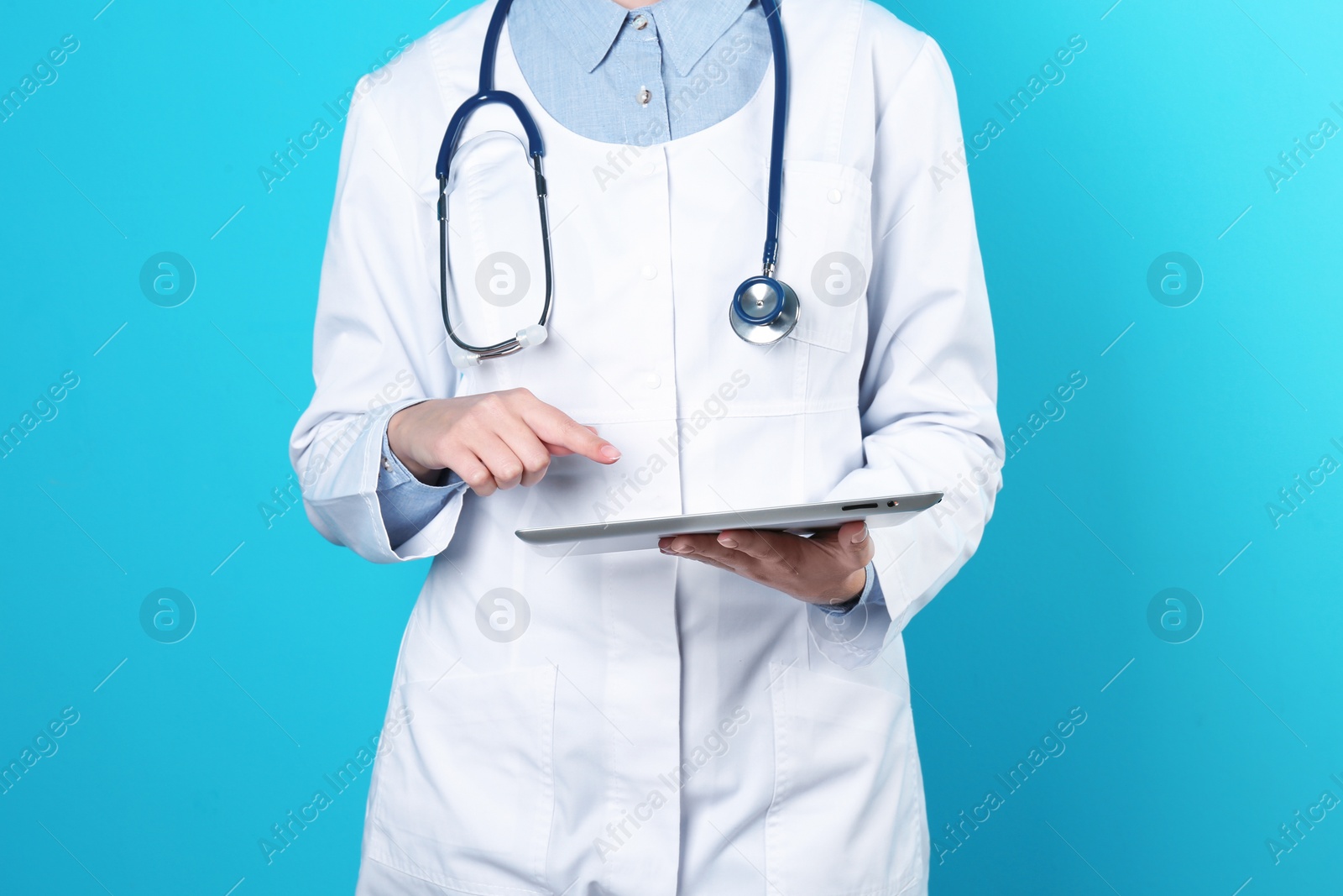 Photo of Female doctor holding modern tablet on color background, closeup