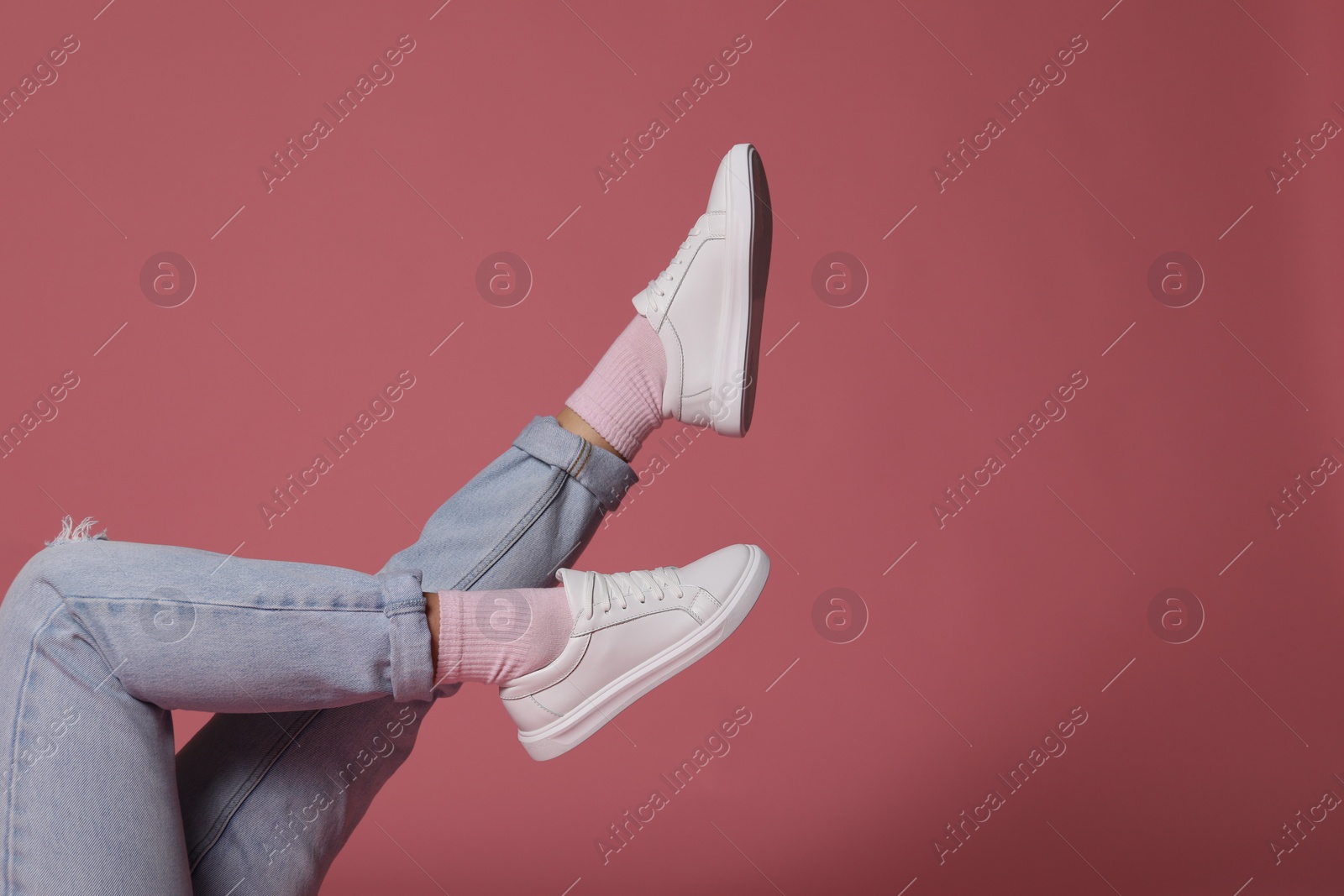 Photo of Woman wearing stylish white sneakers on pink background, closeup. Space for text