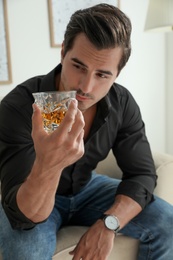 Young man with glass of whiskey at home